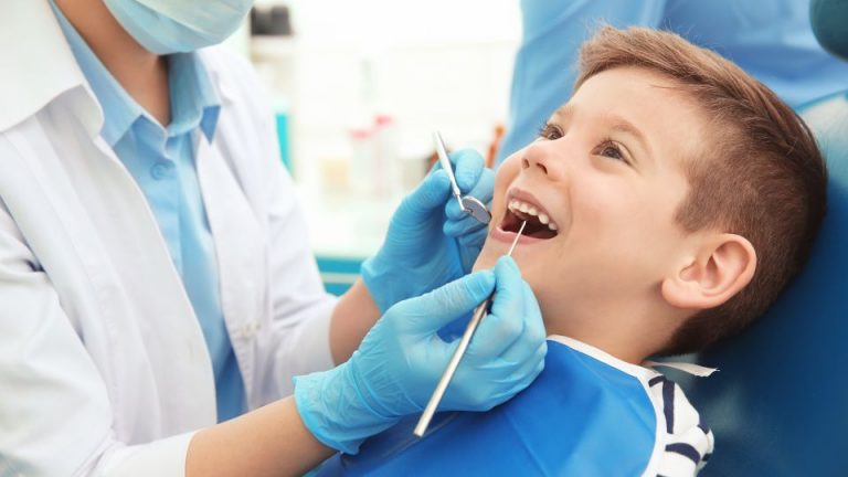 Pediatric Dentist Examining Boy's Teeth with Dental Explorer and Mirror
