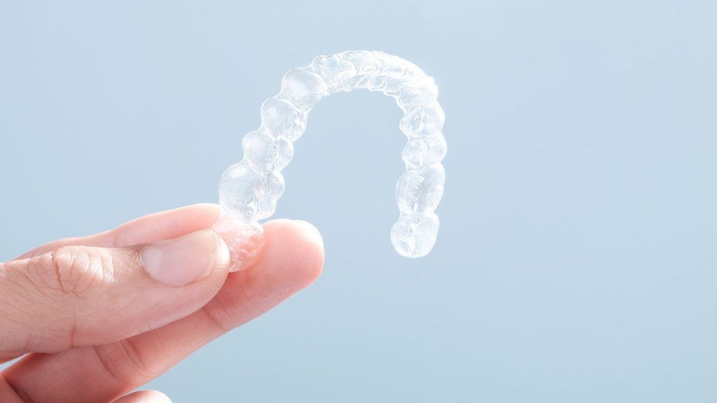Hand Holding Clear Invisalign Braces