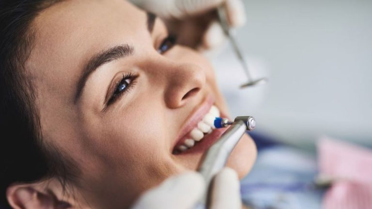 Woman Getting Teeth Whitened By Dental Professional In Clinic
