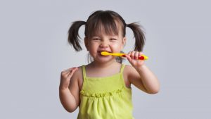 A Girl With Pig Tails Holding A Toothbrush